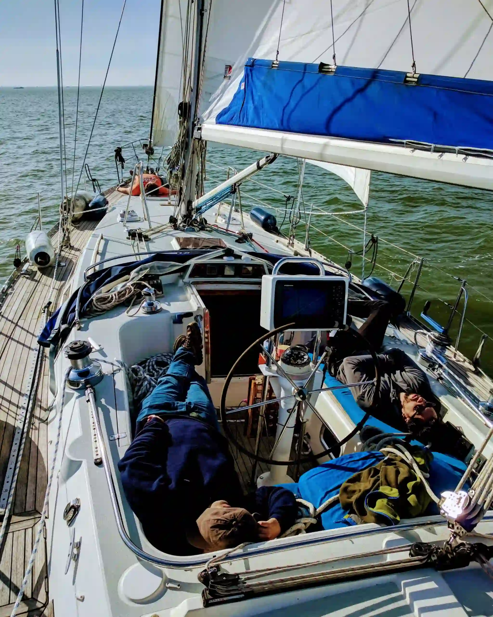 Sailors taking a rest on a sailboat deck with sails hoisted, cruising on Markermeer's gentle waters
